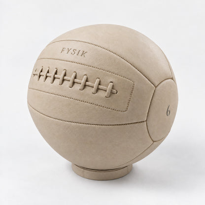 Bonn Medicine Ball — angled view; Grey Ash wood, beige leather and natural stainless steel where applicable. FYSIK studio finish study — October 2026. Representative configuration.
