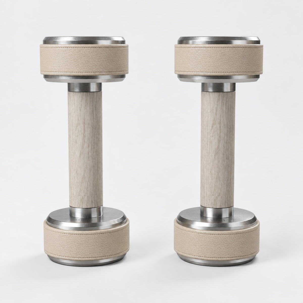 Nak Dumbbell Pair — front view; Grey Ash wood, beige leather and natural stainless steel where applicable. FYSIK studio finish study — October 2026. Representative configuration.