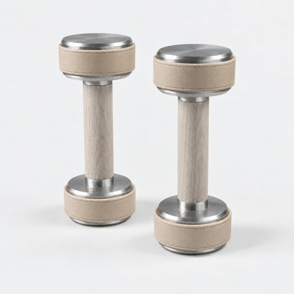 Nak Dumbbell Pair — angled view; Grey Ash wood, beige leather and natural stainless steel where applicable. FYSIK studio finish study — October 2026. Representative configuration.